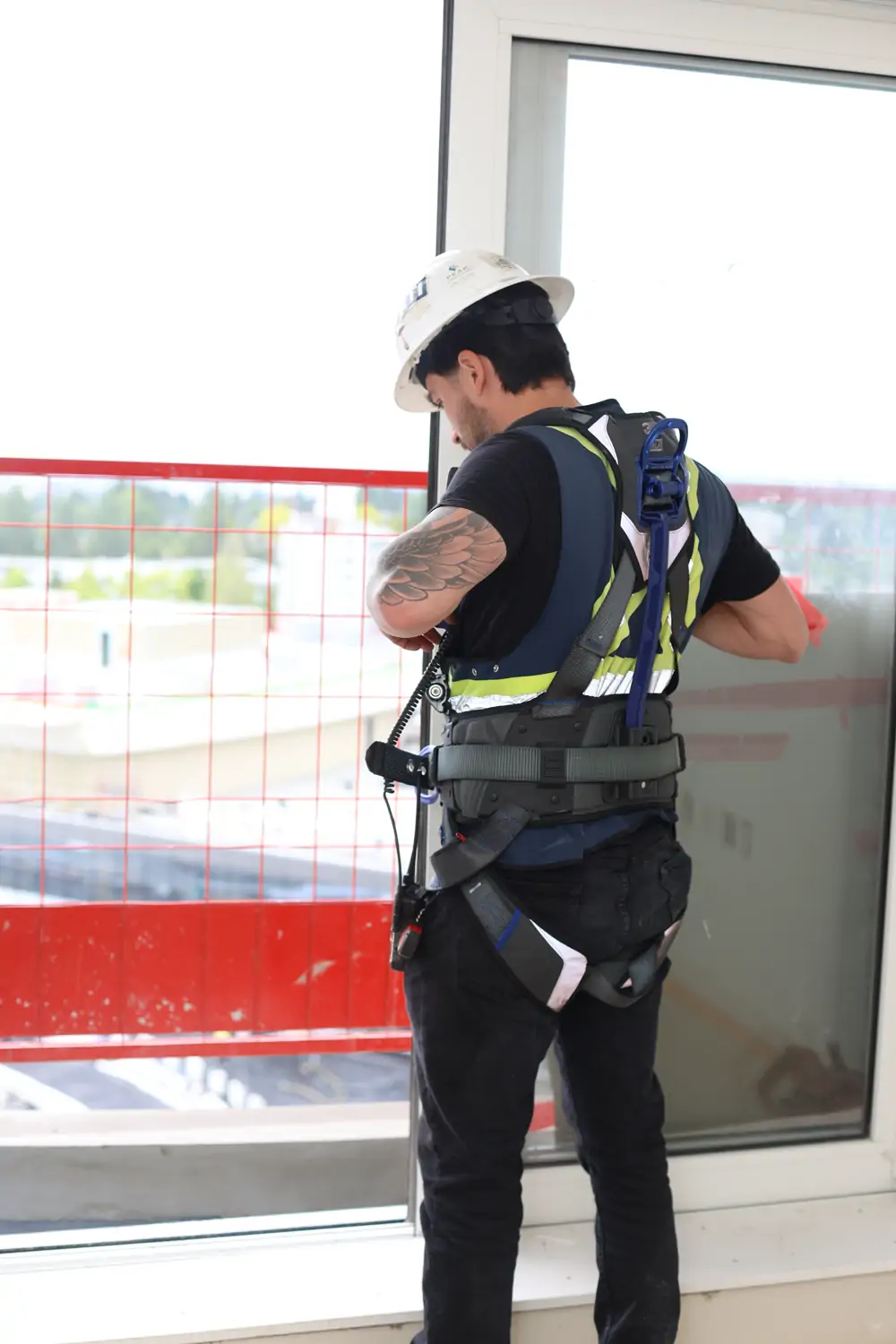 JF West Coast worker in a fall-arrest harness looking out over a job site